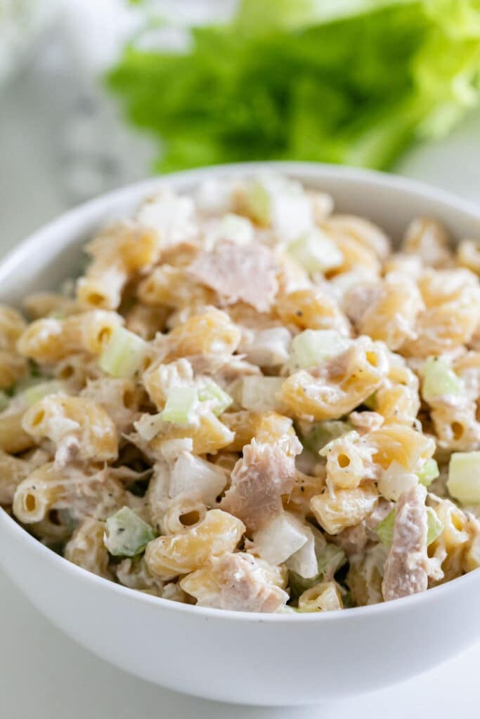 A close up focusing on the tuna mac salad recipe inside a white bowl.