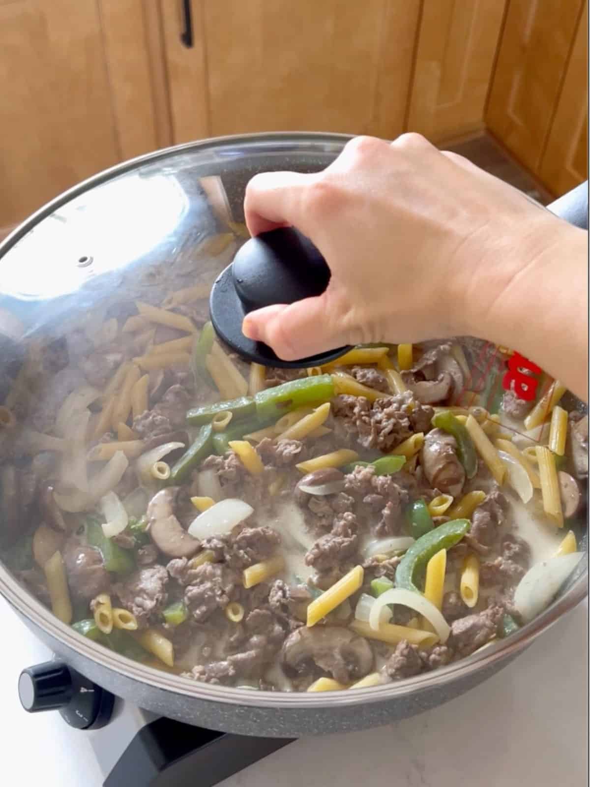 A hand putting cover onto the skillet for cooking.