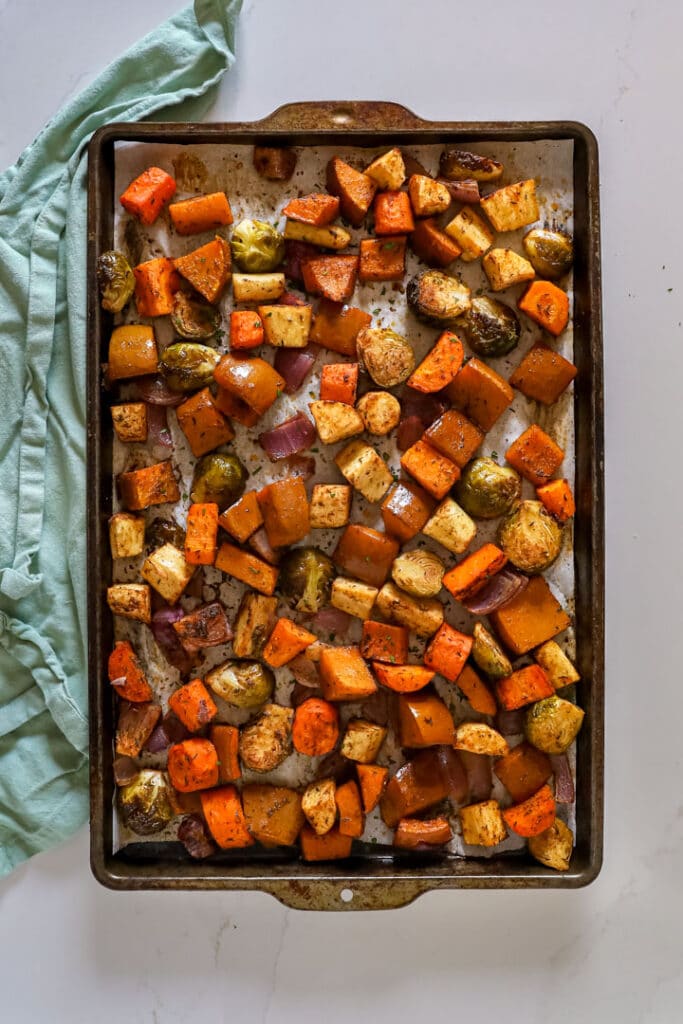 An overhead image of a sheet pan of this roasted veggies recipe with a teal towel next to it.