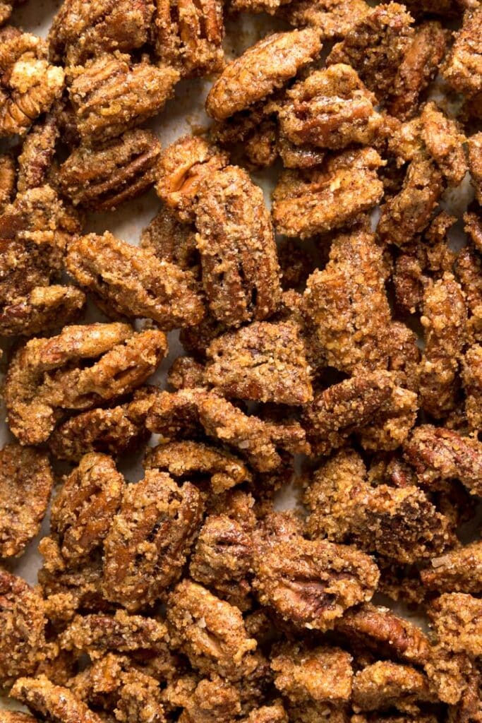 A close up overhead image of candied pecans all together on a pan.