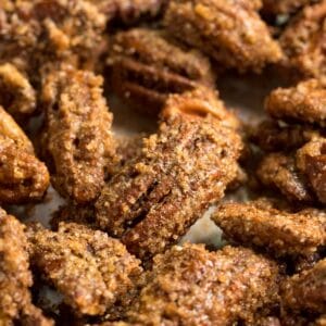 A side angle close up image of candied pecans focusing on one.