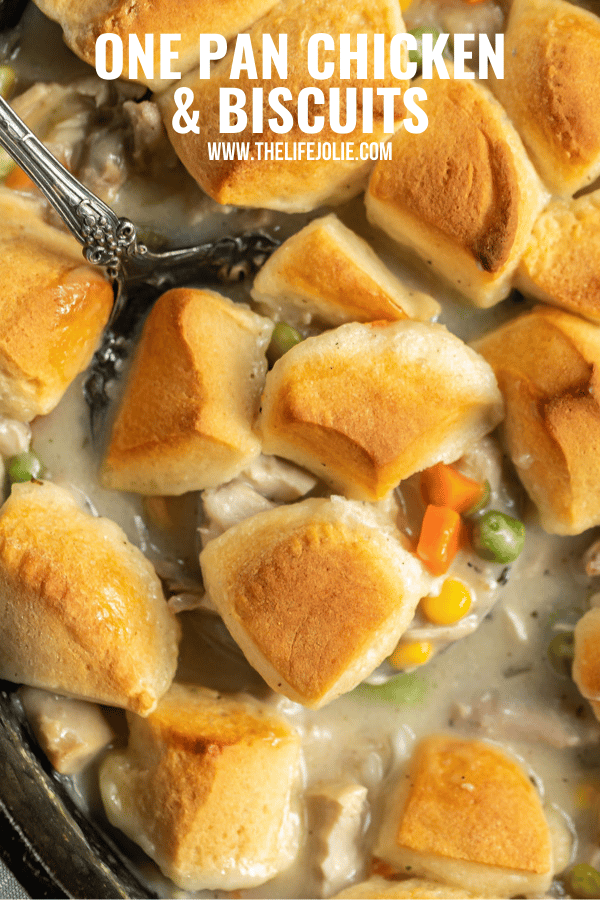 A close up overhead image of a spoon in a pan of chicken and biscuits.