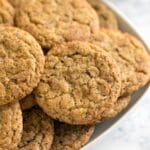 A close up image focusing on a snickerdoodle cookie in a pile of other snickerdoodle cookies.