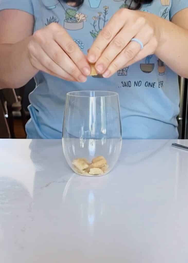 Image of hands crumbling cookies into clear glass