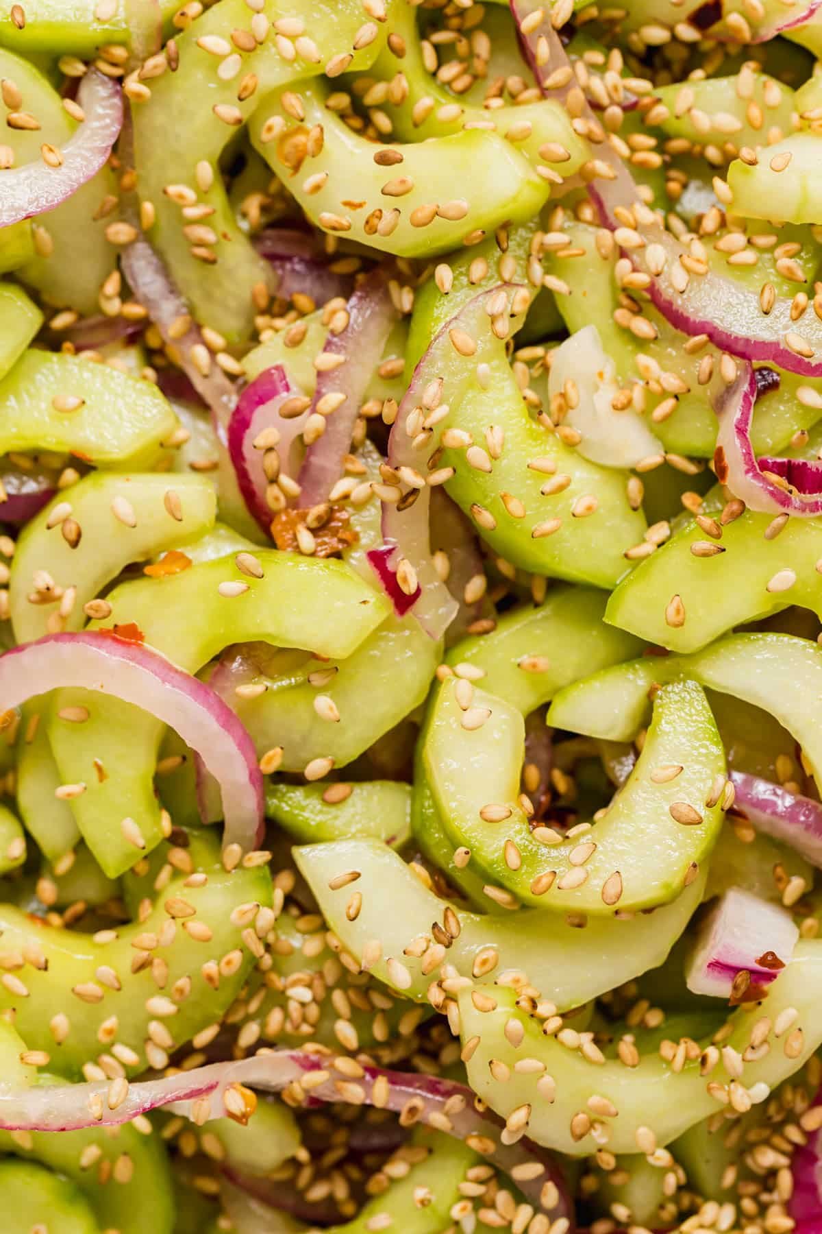 A zoomed in image of the cucumber and onions in the salad with red pepper flakes and sesame seeds sprinkled on.