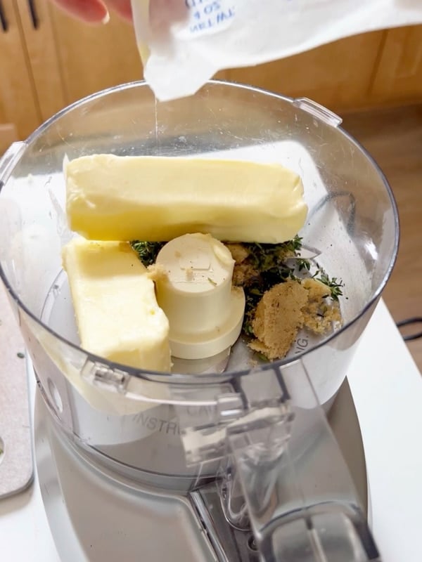 A food processor with the compound butter ingredients in it.