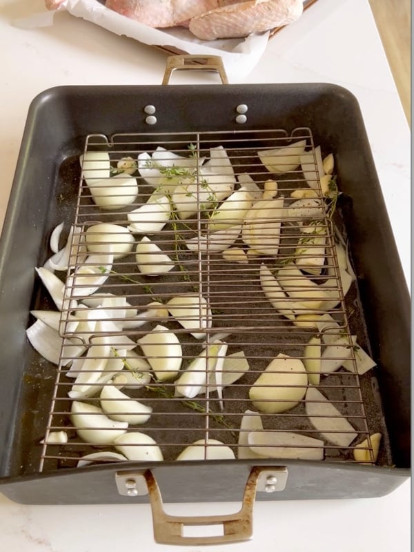 An image of the prepared roasting pan with vegetables at the bottom and a rack.
