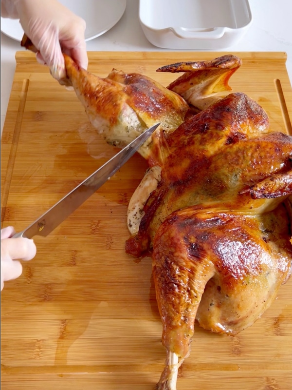 Hands carving a turkey.