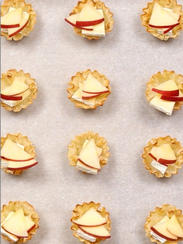 An overhead image of phyllo cups with SnapDragon Apples added in them spread on a parchment lined baking sheet.