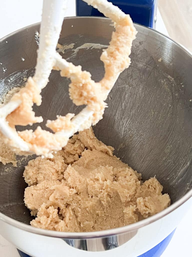 Butter and sugars creamed together in the bowl of a blue stand mixer