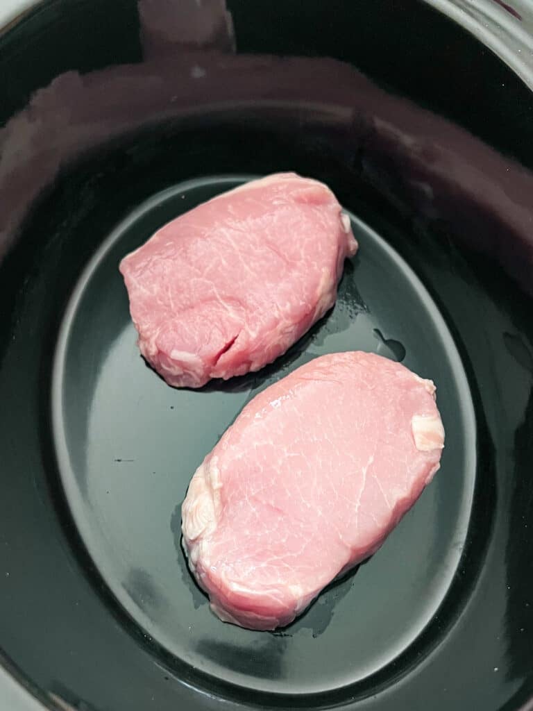 Two boneless pork chops in a crockpot.