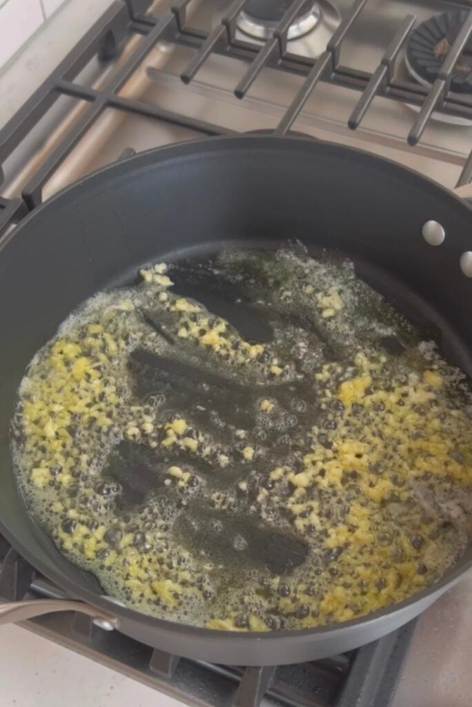 An image of garlic, butter and oil cooking in a skillet.