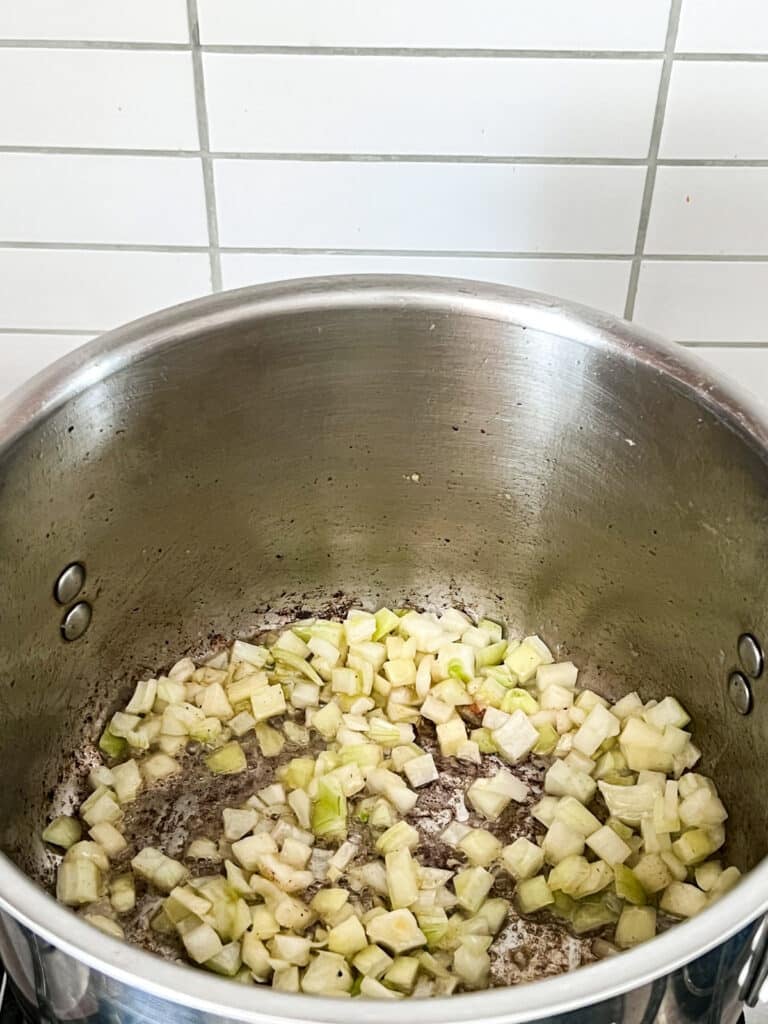 Onions sautéing in a pot on a stove.