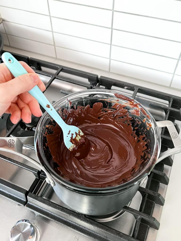 Chocolate melting in a double boiler on a stove and being stirred.