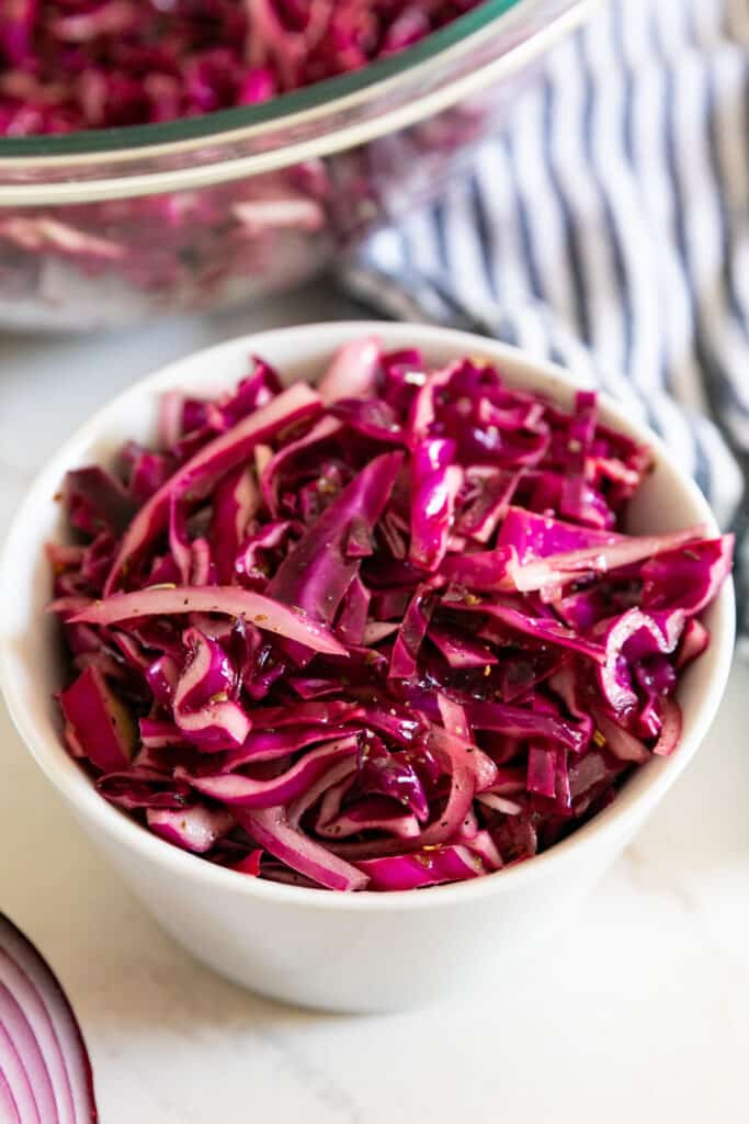 A close up image of a white bowl of purple cabbage salad.