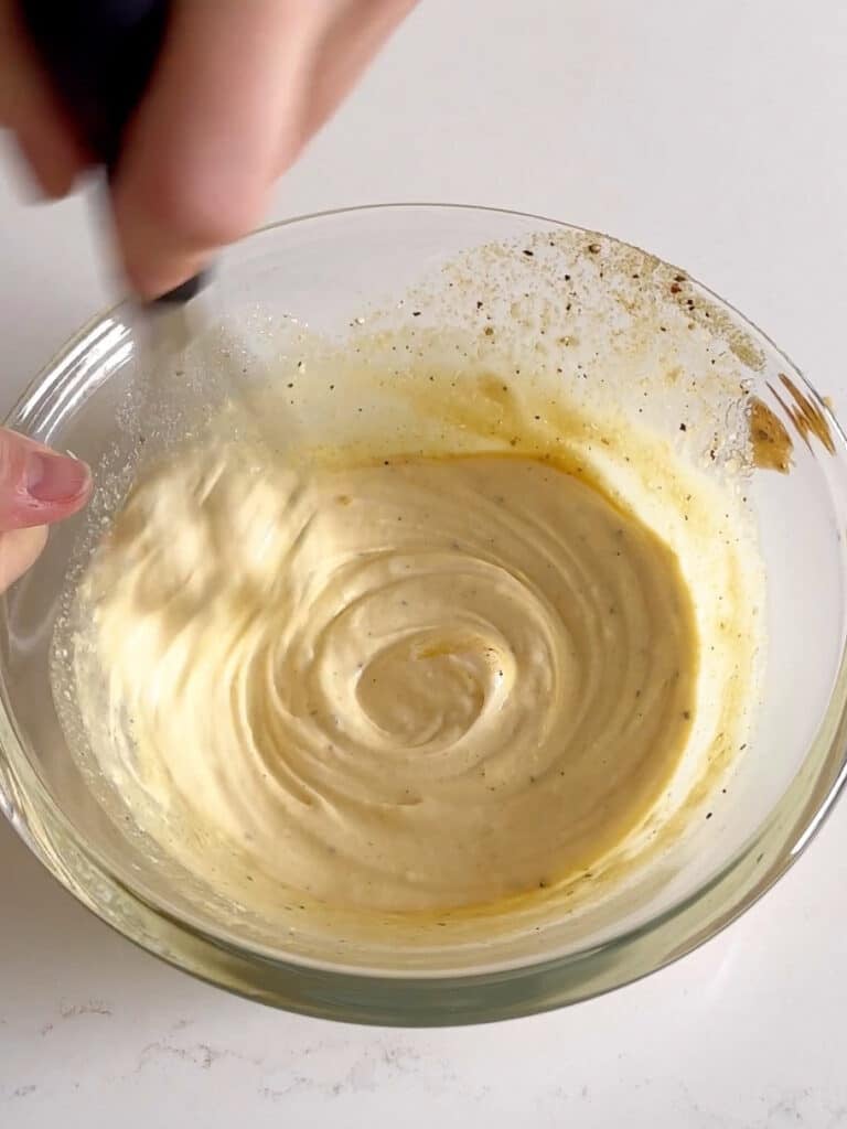 A bowl of the dressing being whisked together.