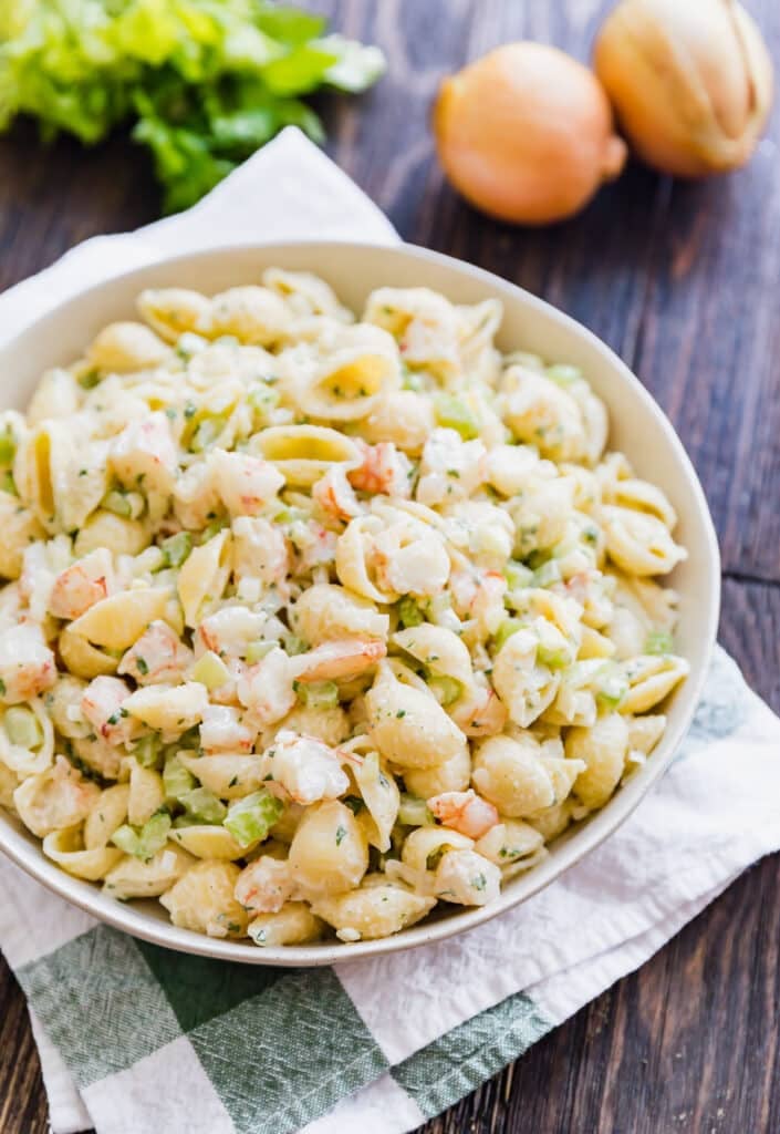 A bowl of shrimp mac salad on a green and white towel.