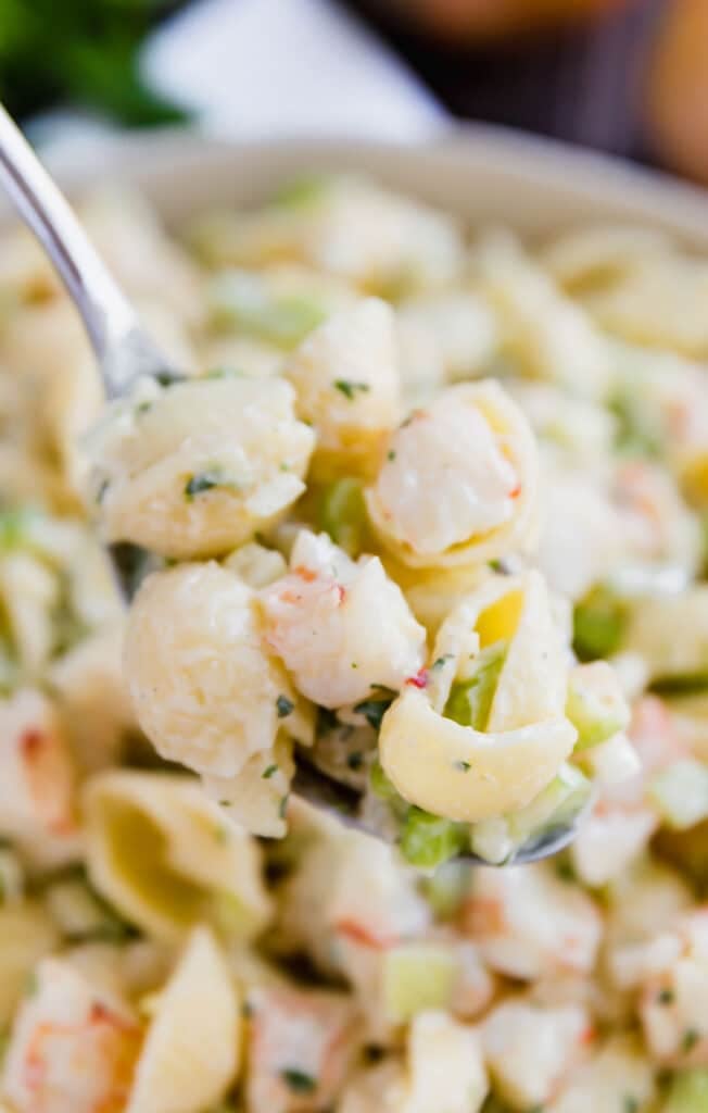 A close up image of a spoon holding a scoop of this shrimp macaroni salad recipe.
