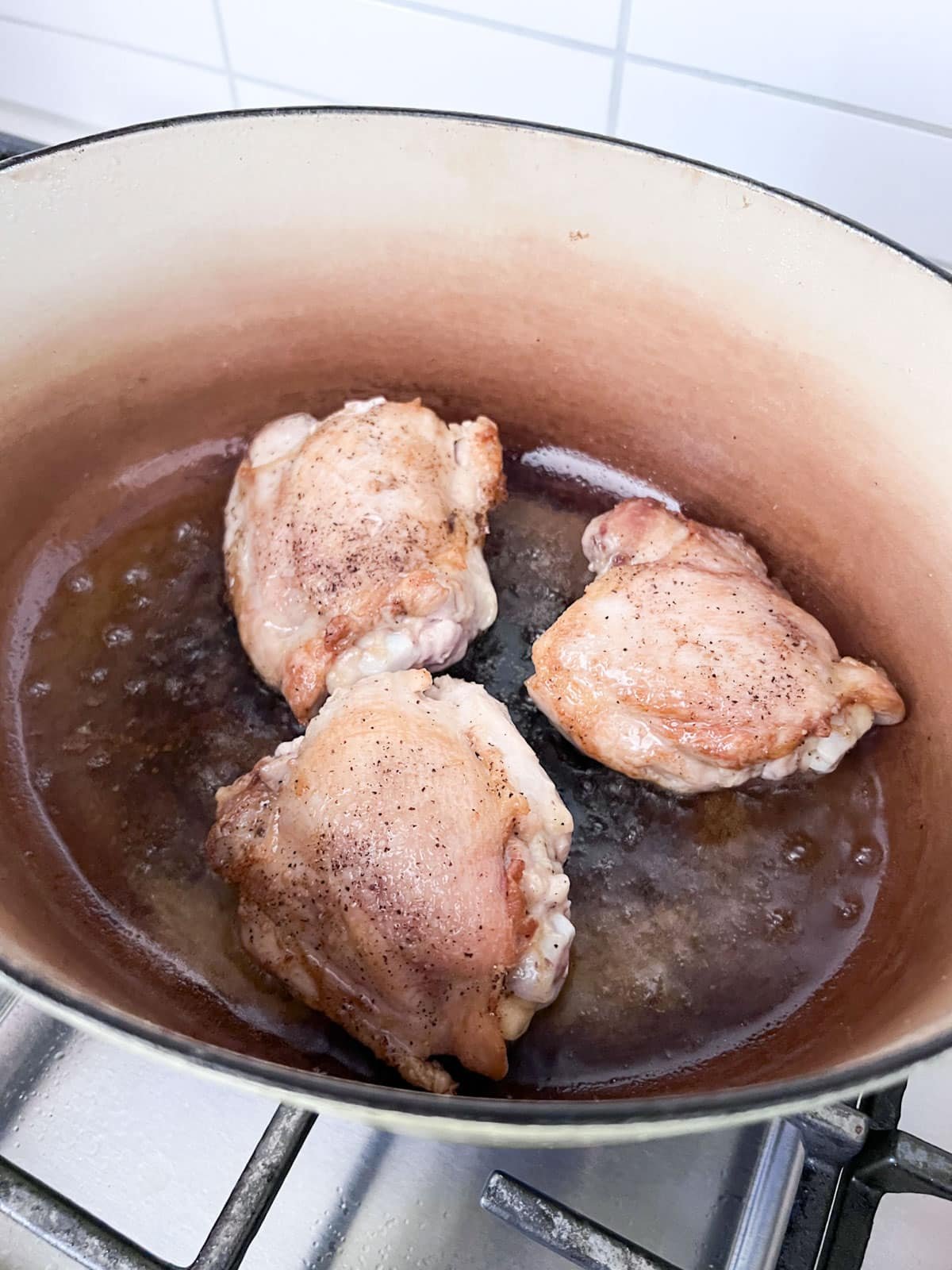 Chicken pieces browning in oil in the dutch oven.