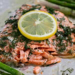 A close up image of a piece of salmon on a pan with the front of it flaked to show the inside of the salmon.
