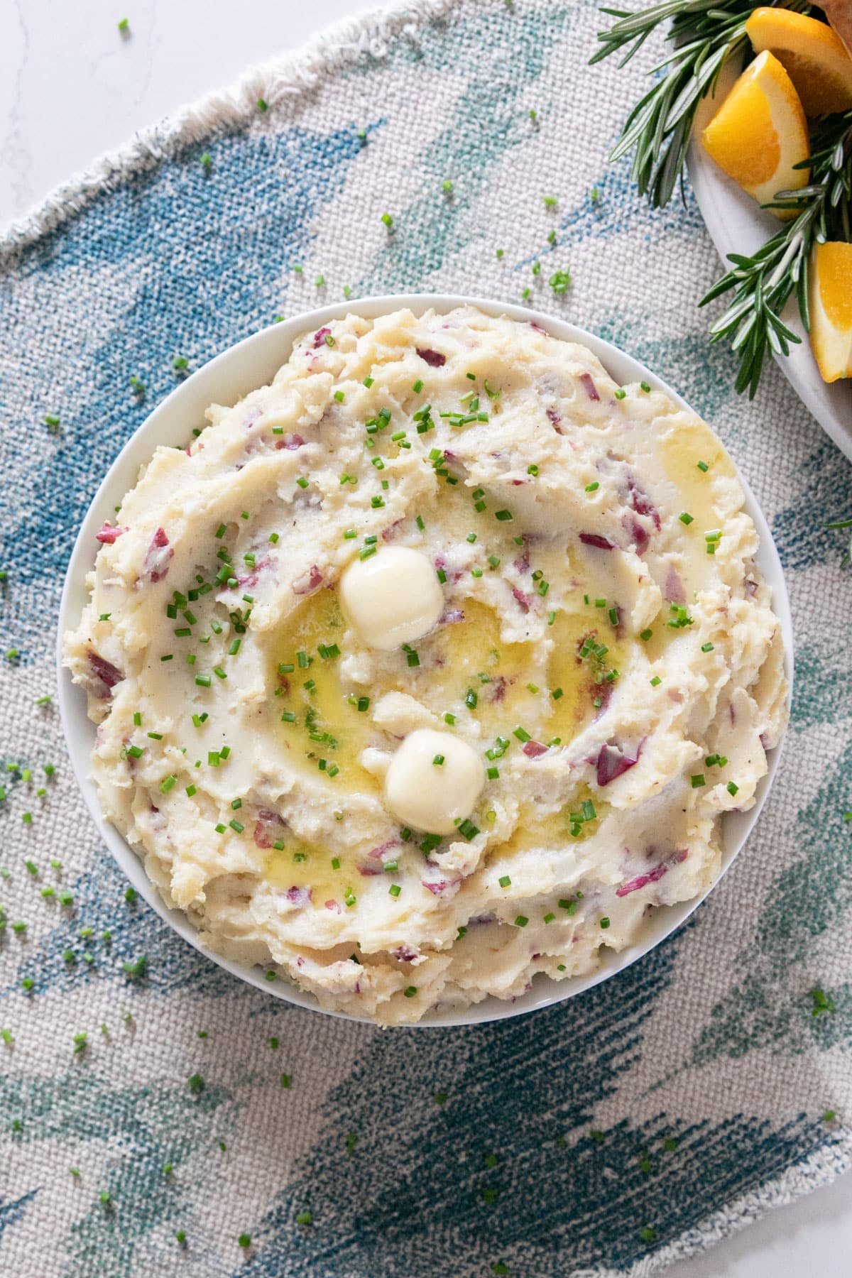 An overhead image of mashed potatoes with melting butter and chives on top.