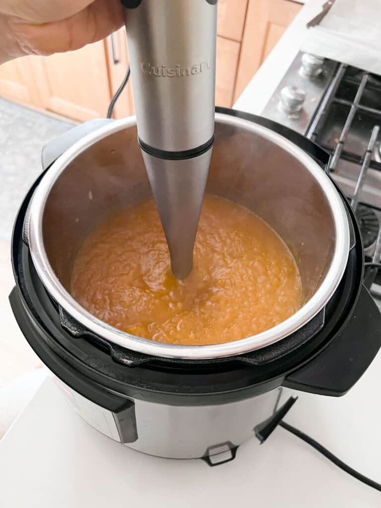 Soup being pureed by a stick blender in the Instant Pot.