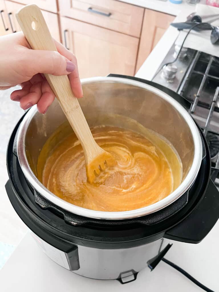 A spoon stirring cream into soup in the Instant Pot.