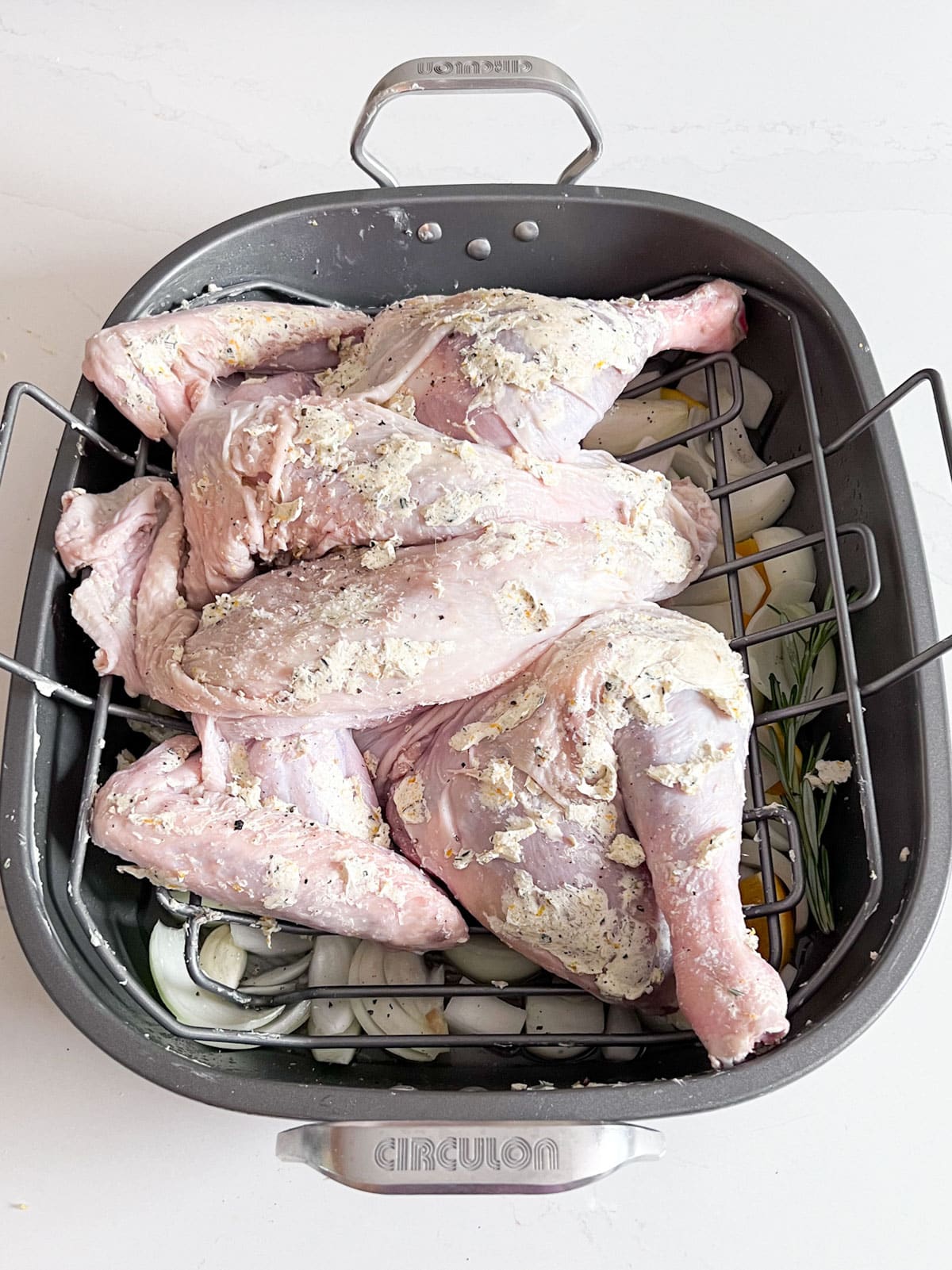 A spatchcocked turkey covered in butter in a prepared pan.