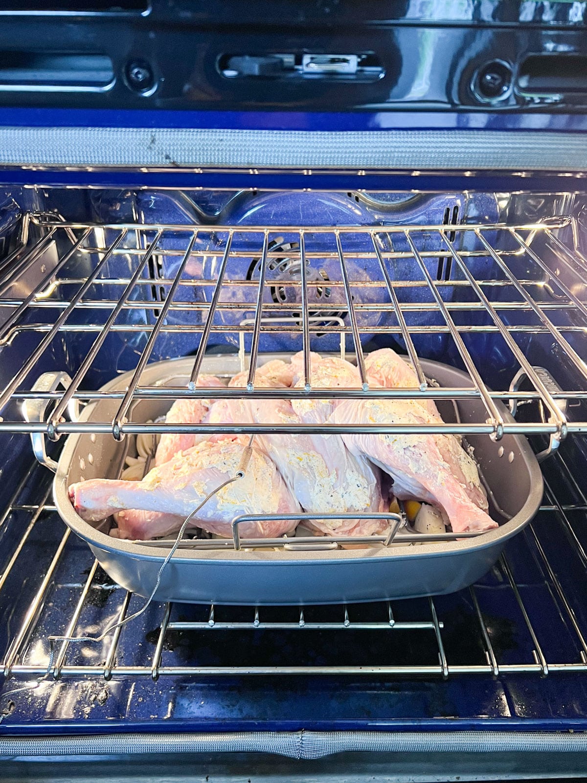 A spatchcocked turkey in a pan that's just been placed in the oven.