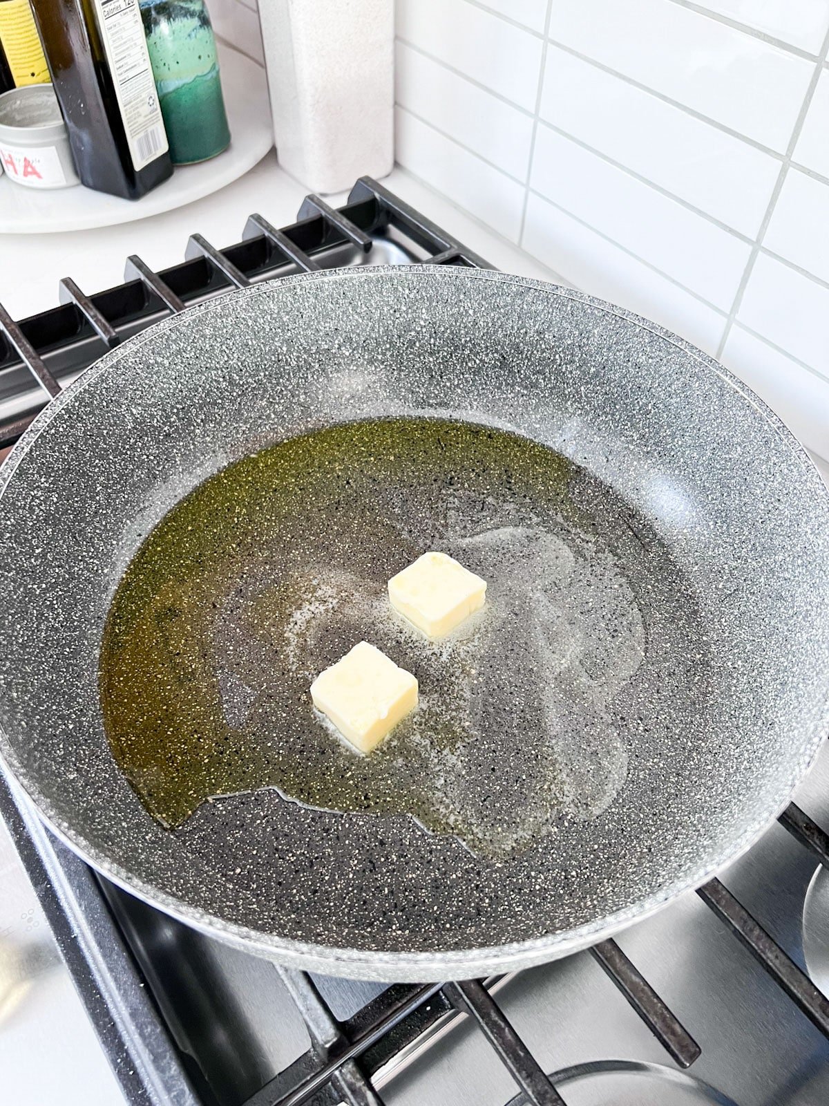 A skillet on a stove with butter and oil melting together.