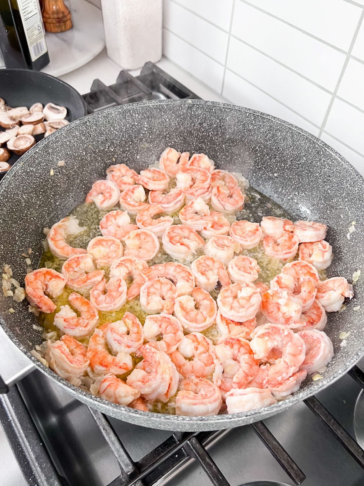 Shrimp sautéing in a pan on a stove.