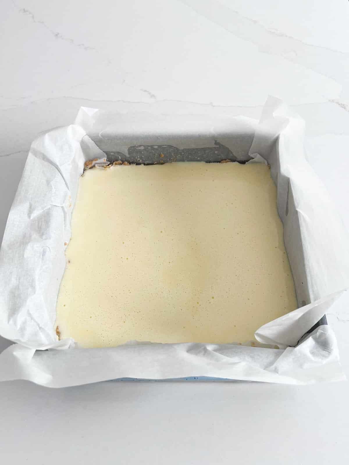 A baking pan with the baked shortbread crust and lemon curd poured on top.