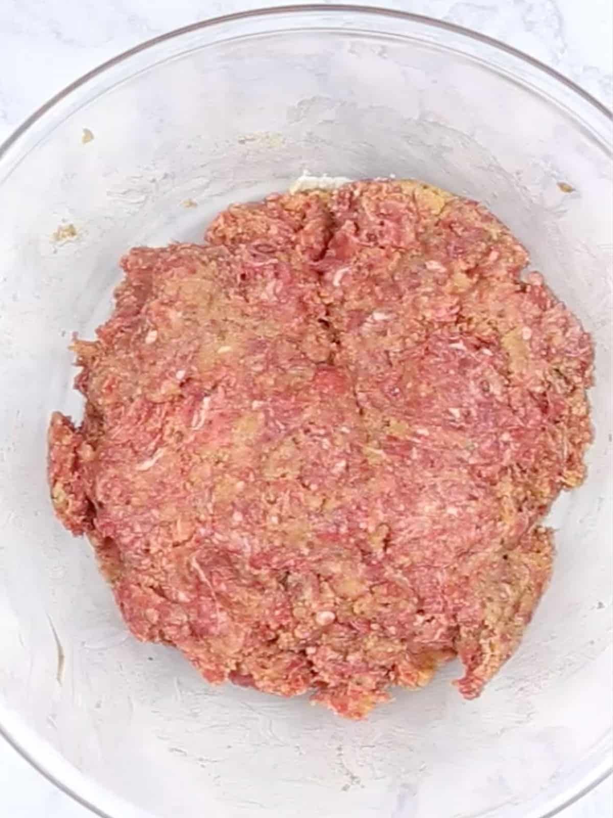 The meatloaf ingredients combined in a glass bowl.