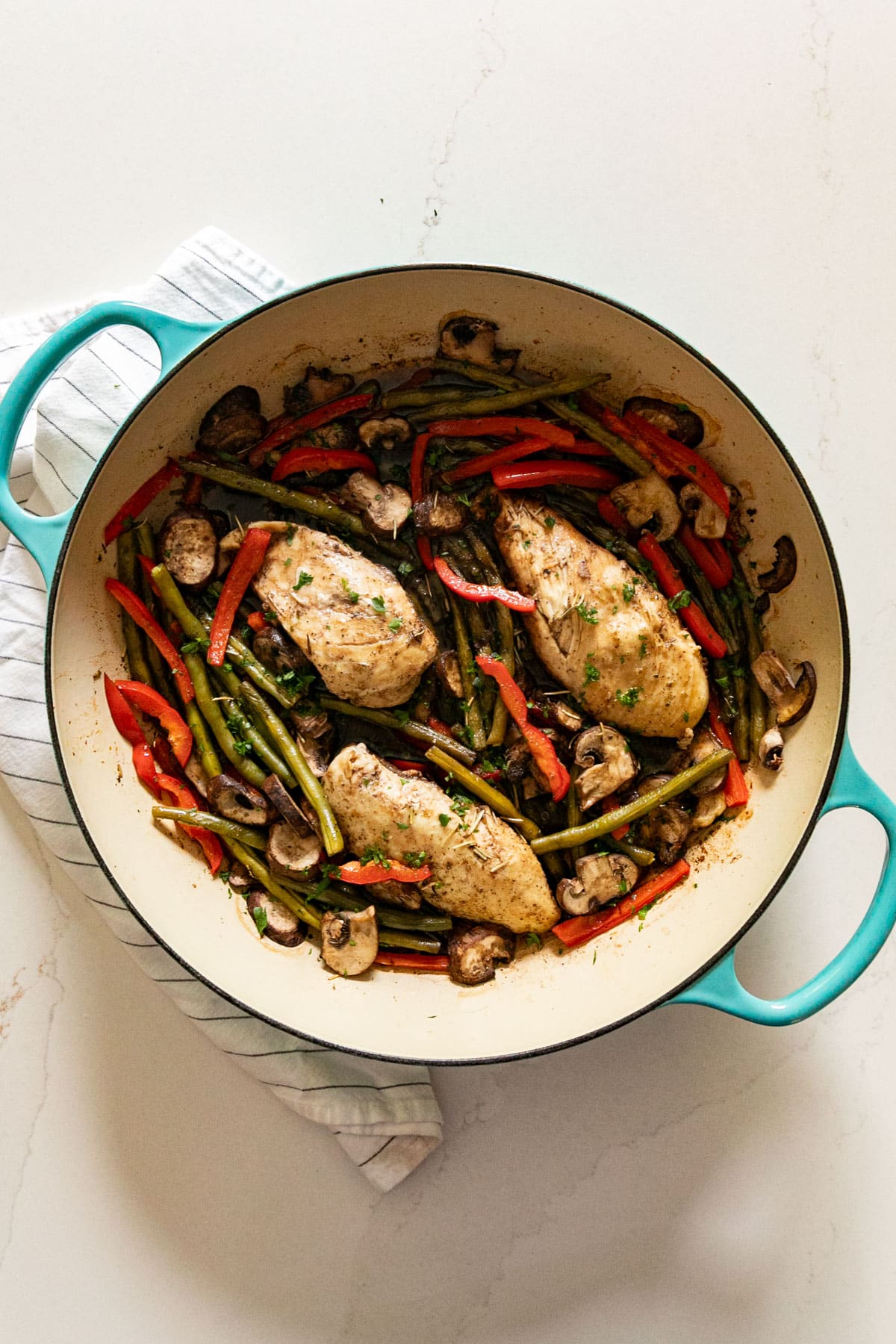 An overhead image of a blue pan with balsamic chicken nestled in vegetables.
