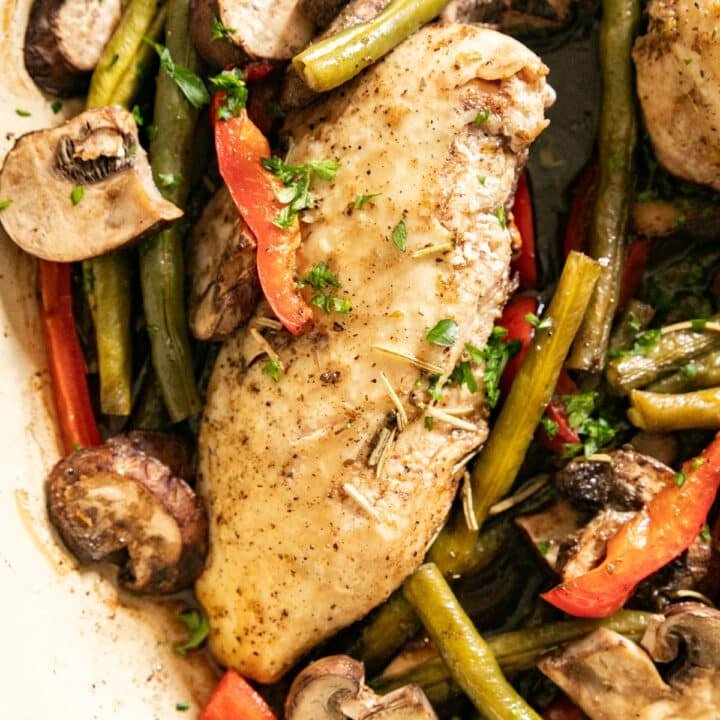 A close up overhead image of the chicken breast nestled in a skillet of green beans, peppers and mushrooms.
