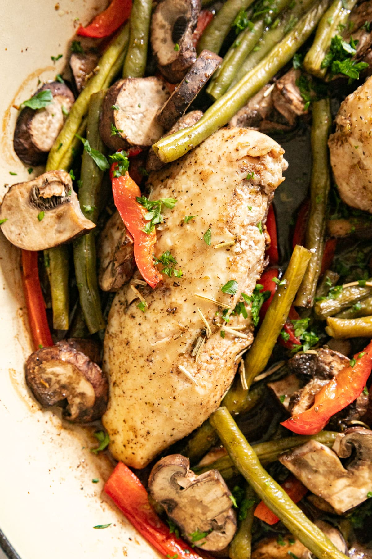 An close up overhead image of the chicken breast nestled in a skillet of green beans, peppers and mushrooms.