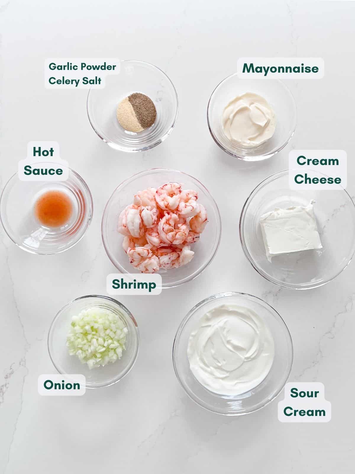 An overhead image of the shrimp dip ingredients labels in glass bowls.