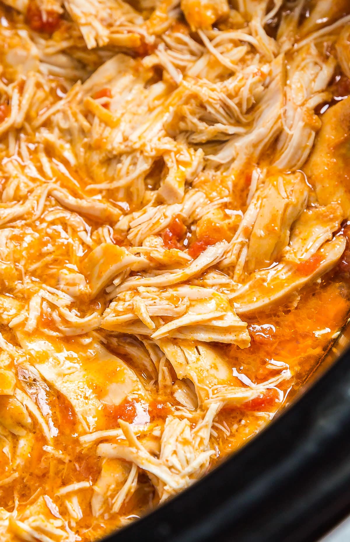 A close up image of shredded chicken taco meat in a slow cooker.