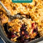 The corner of a pan of blueberry dump cake with a spoon in it revealing the berry mixture along with the crust.
