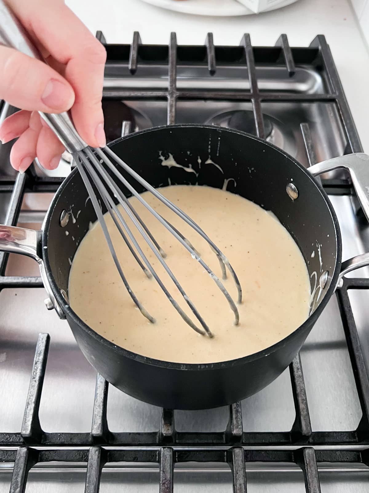 Cheese sauce being whisked in the pan.