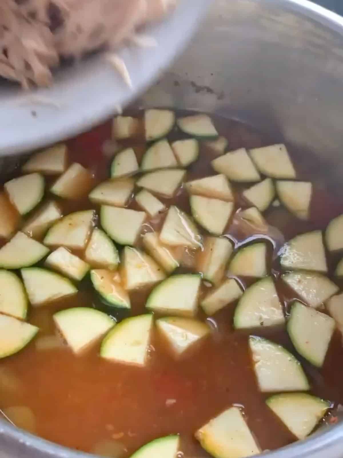 shredded chicken about to be poured into the pot which now has zucchini added to it.
