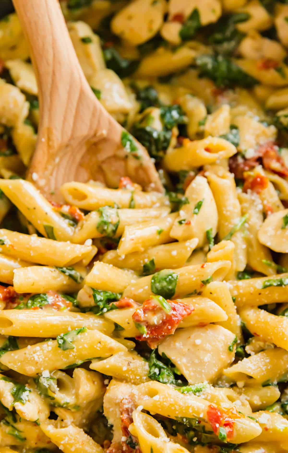 A close up image of Florentine pasta in a skillet with a wooden spoon in the background.