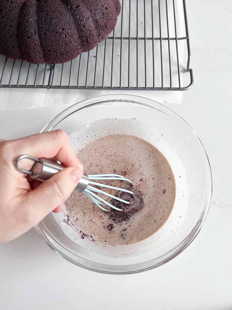 A hand beginning to whisk heavy cream and chocolate in a glass bowl.
