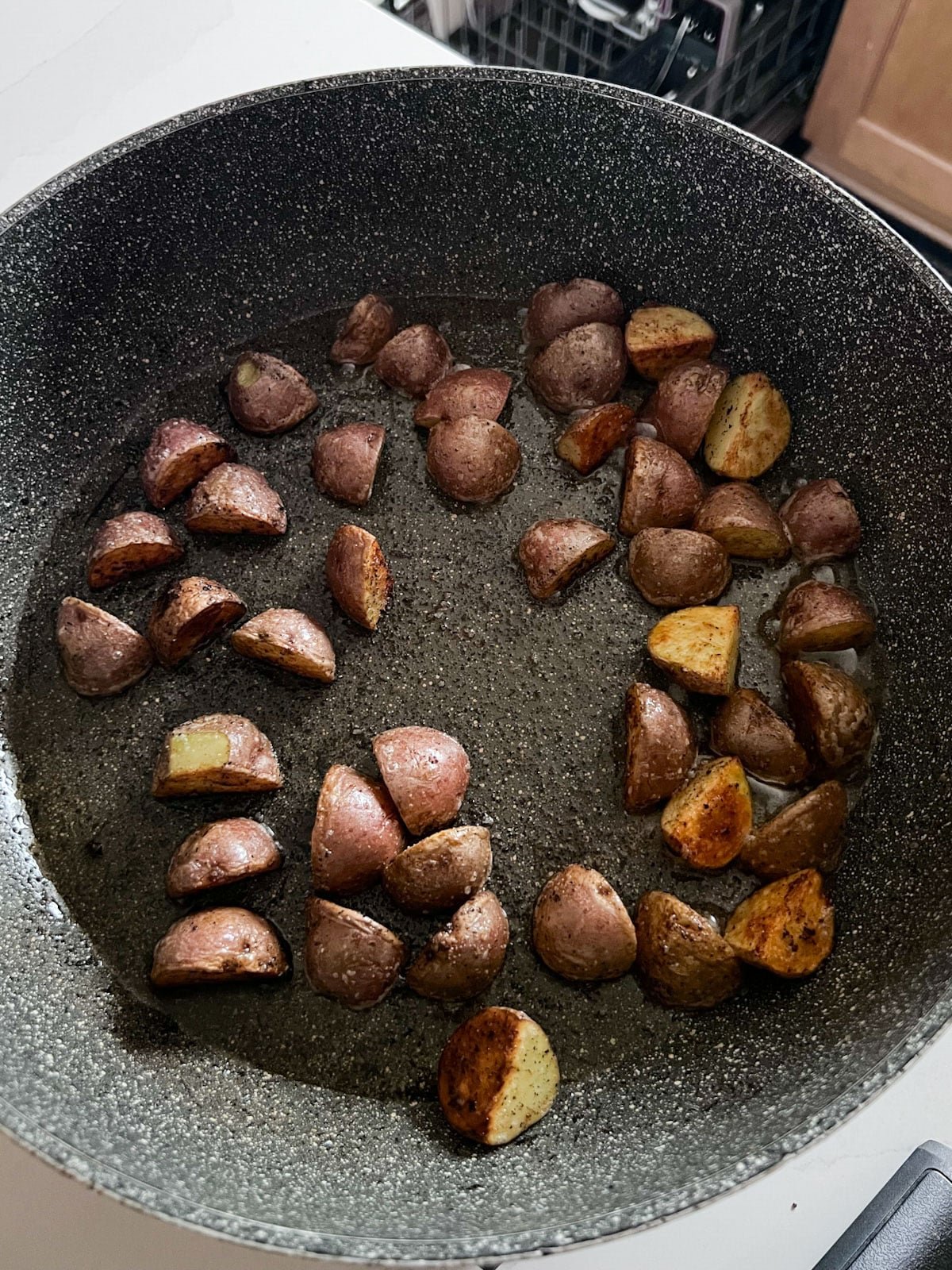Almost fully cooked potatoes cooking in a skillet.