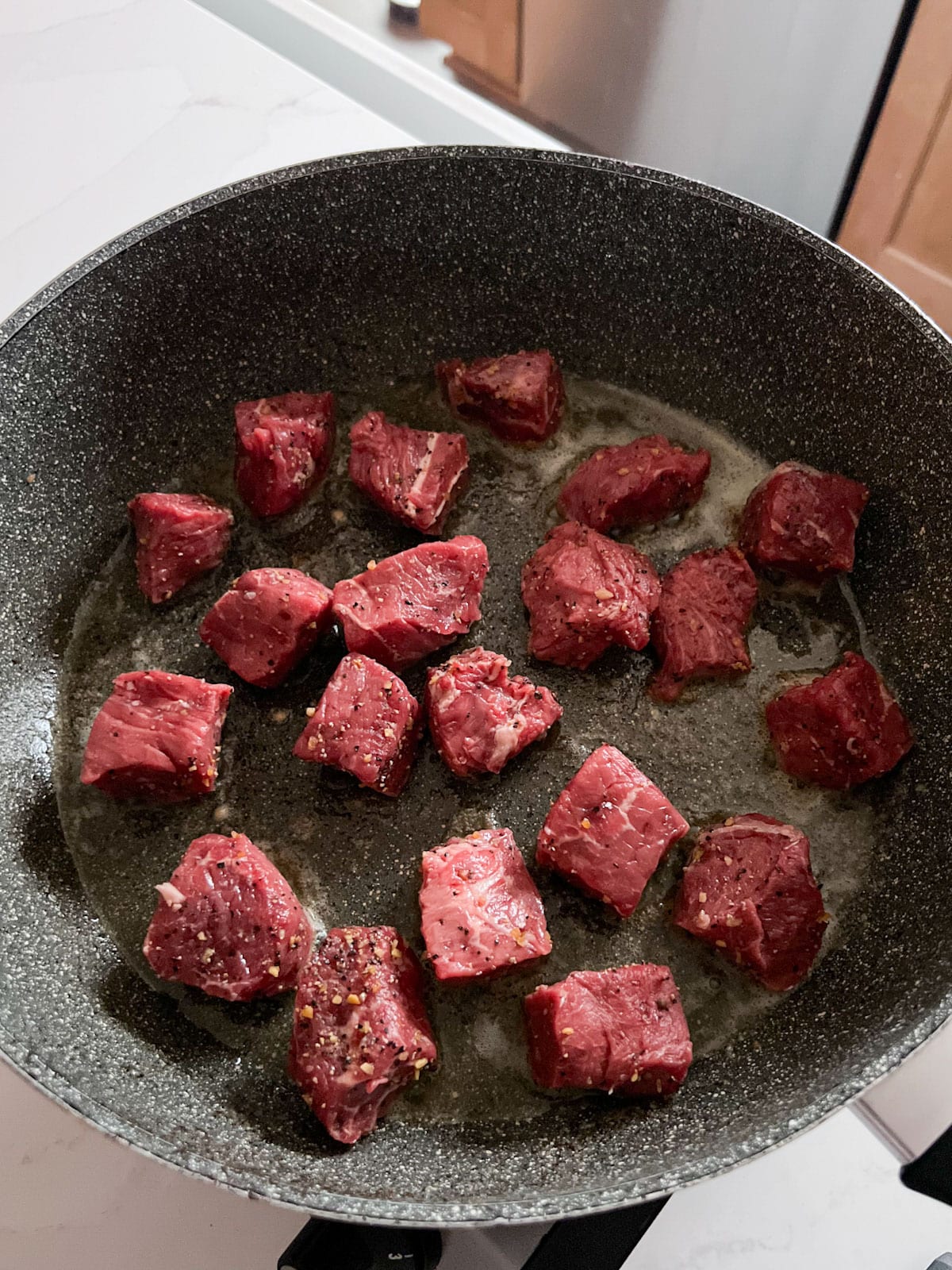 Raw beef chunks added to the melted butter in the skillet.