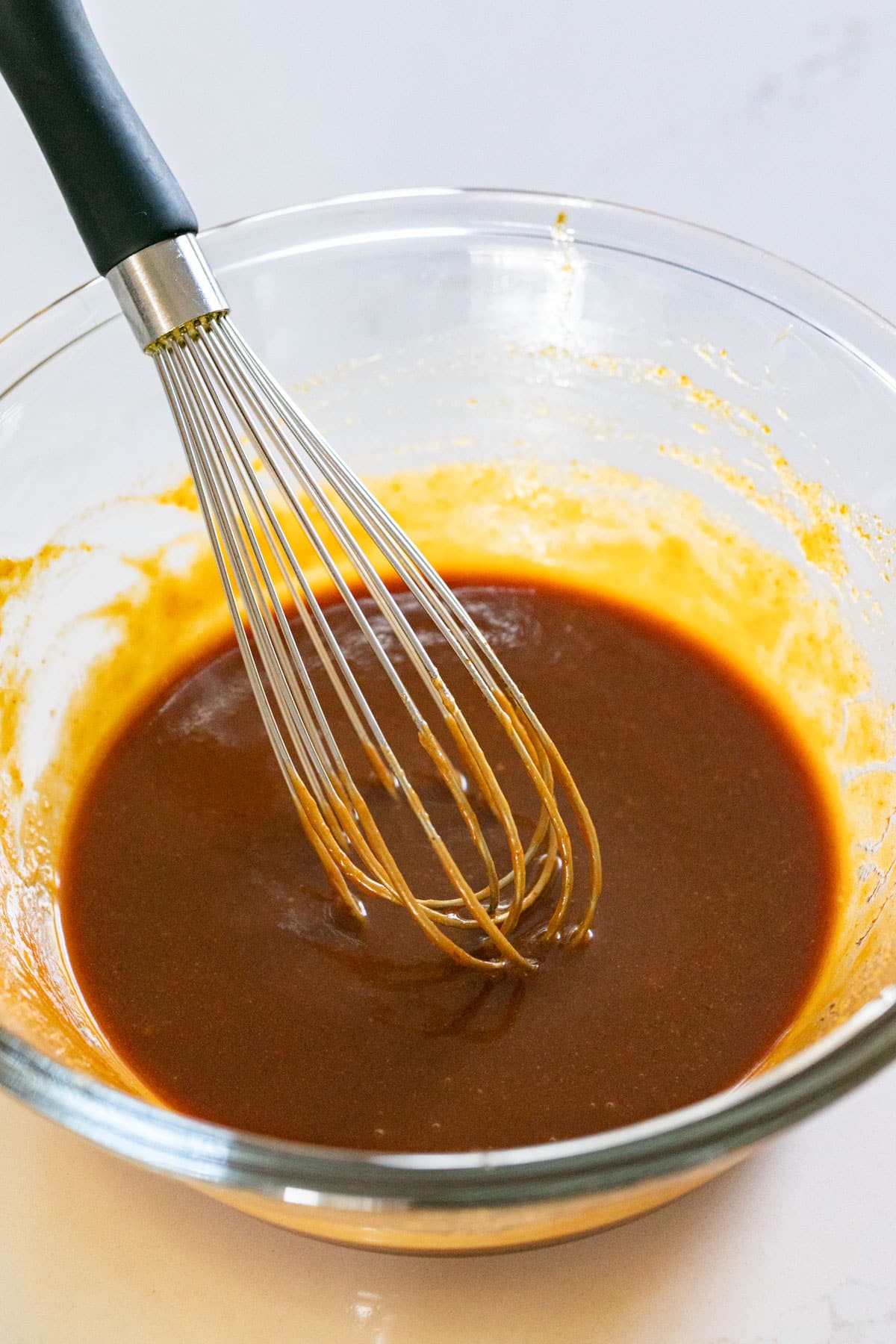 Asian salad dressing recipe in a glass bowl with a whisk in it.
