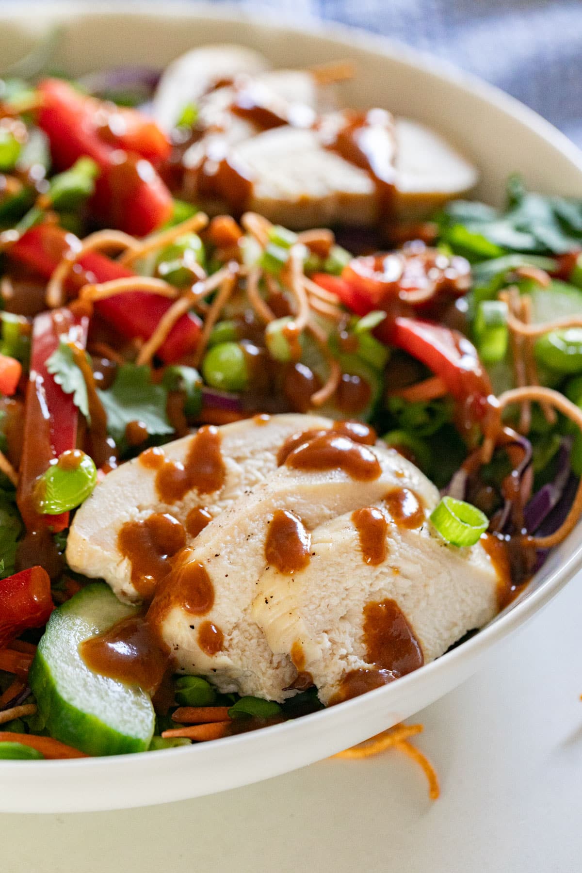 A close up image of the chicken in the Asian salad drizzled with the peanut dressing.