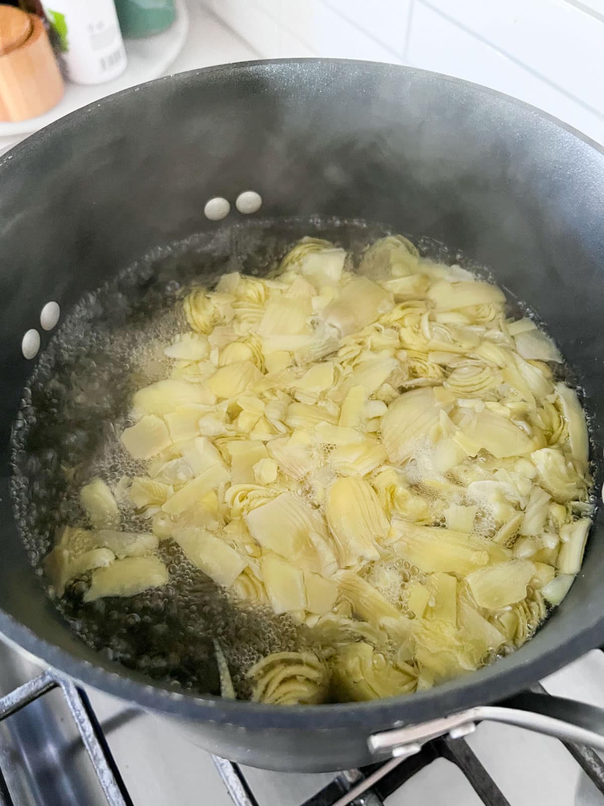 Artichoke hearts boiling in a large pan.