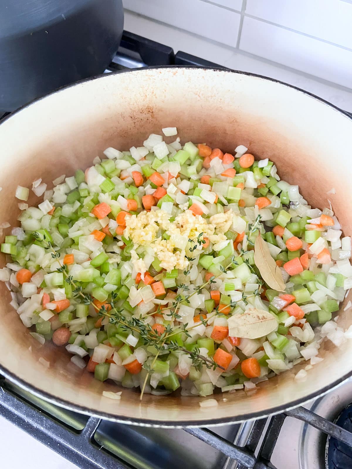Veggies in a dutch oven cooking on a stove.
