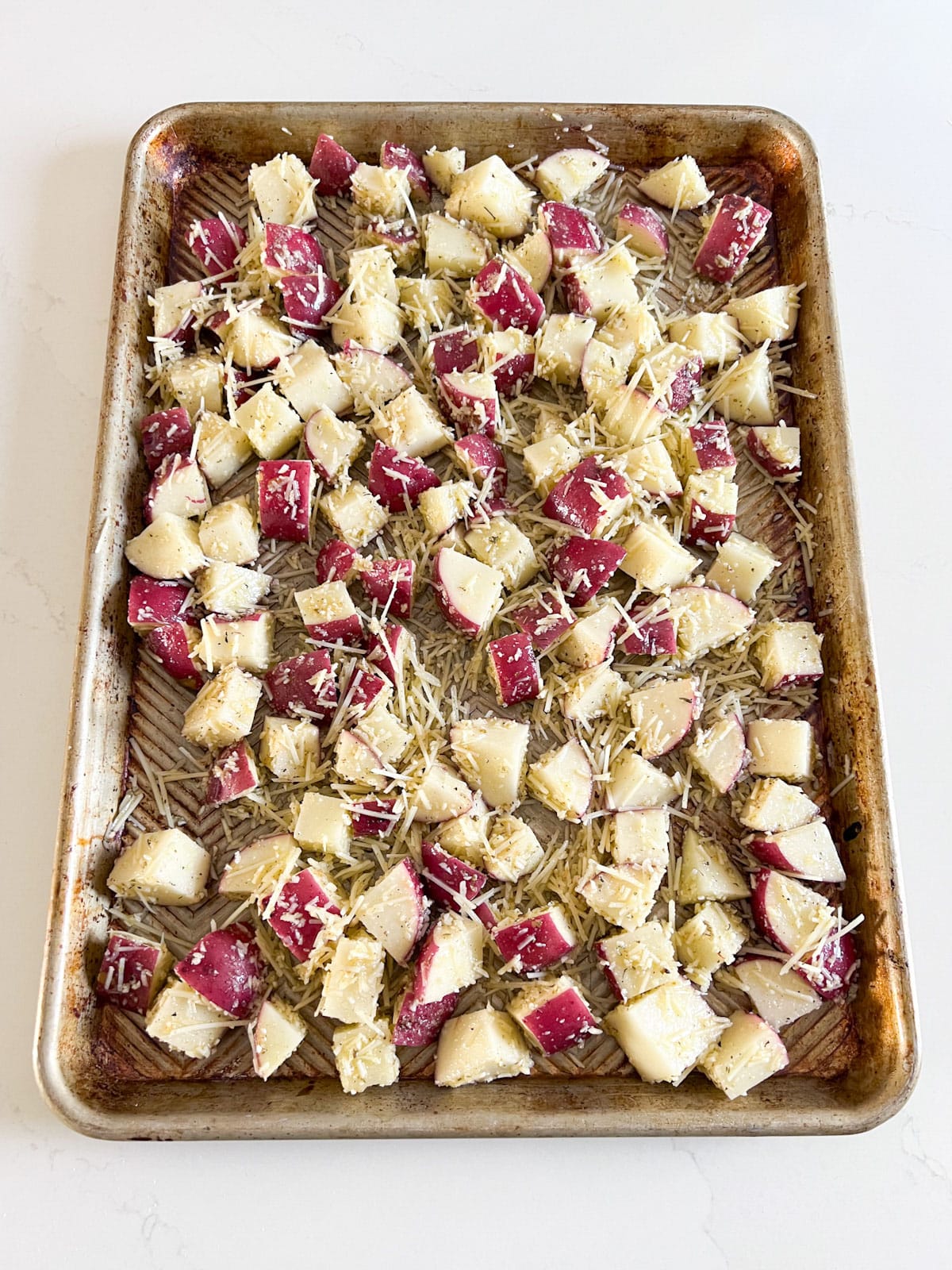 A sheet pan with the potato and cheese mixture spread on it.